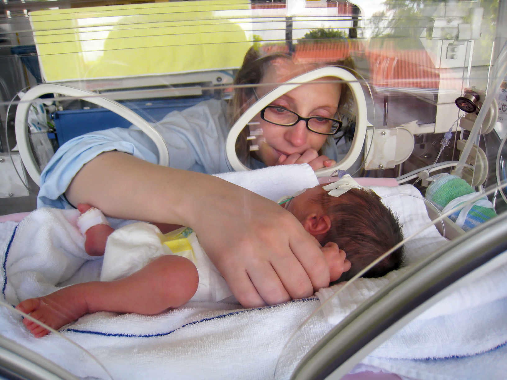 mom touching baby in NICU incubator